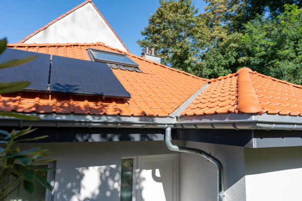 Maison en crépi blanc avec toiture en tuile orange et panneaux photovoltaïques