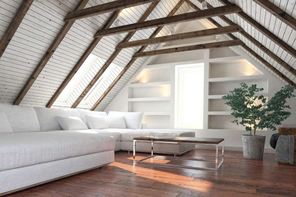 Isolation d'un grenier aménagé en une pièce de vie avec un salon blanc, une table et une plante verte
