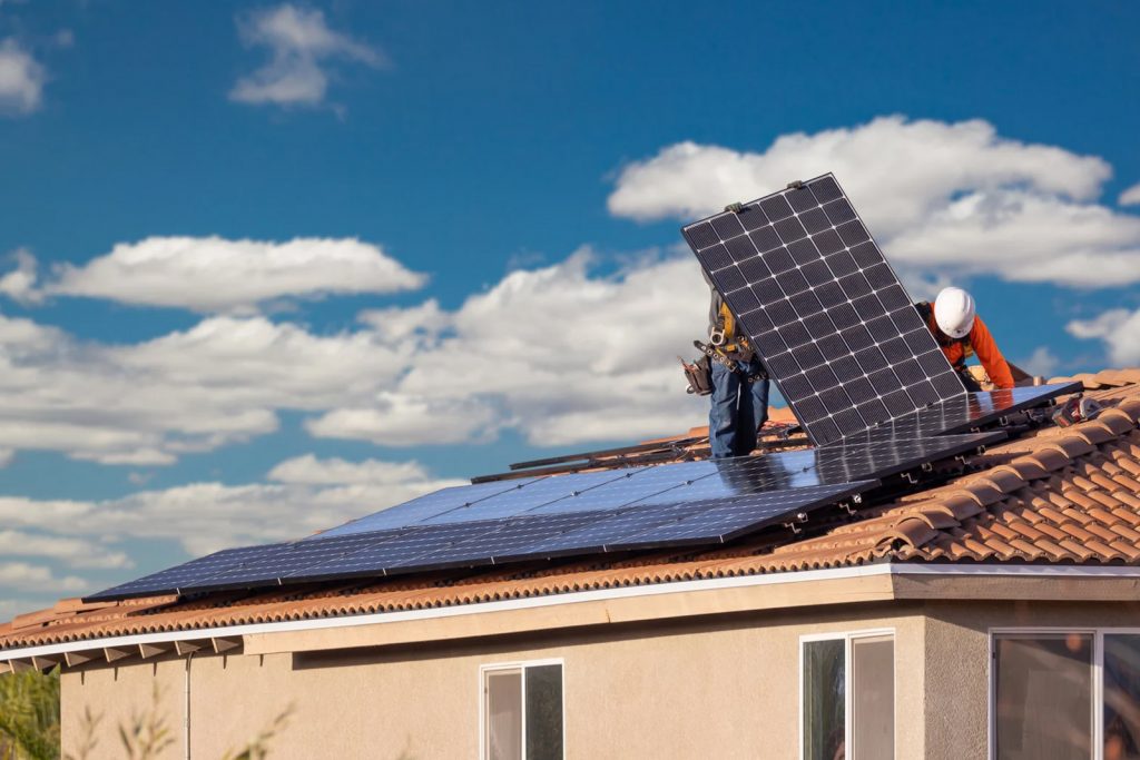 Ouvrier en orange sur un toit en train de poser des panneaux photovoltaïques