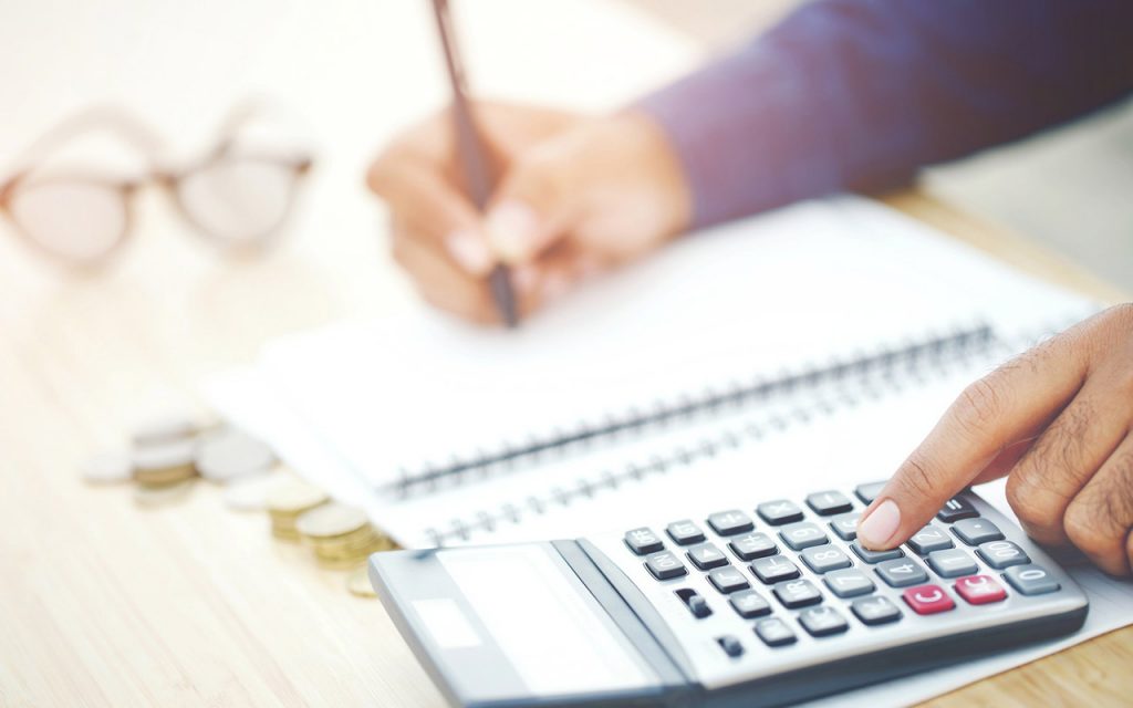 Homme utilisant une calculatrice et écrivant sur un carnet sur une table